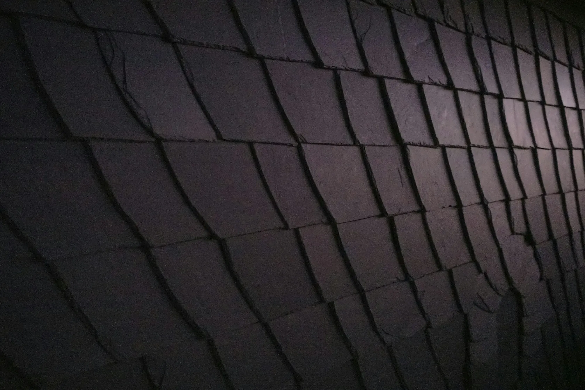 Overlapping dark slate-style shingles curving across a roof