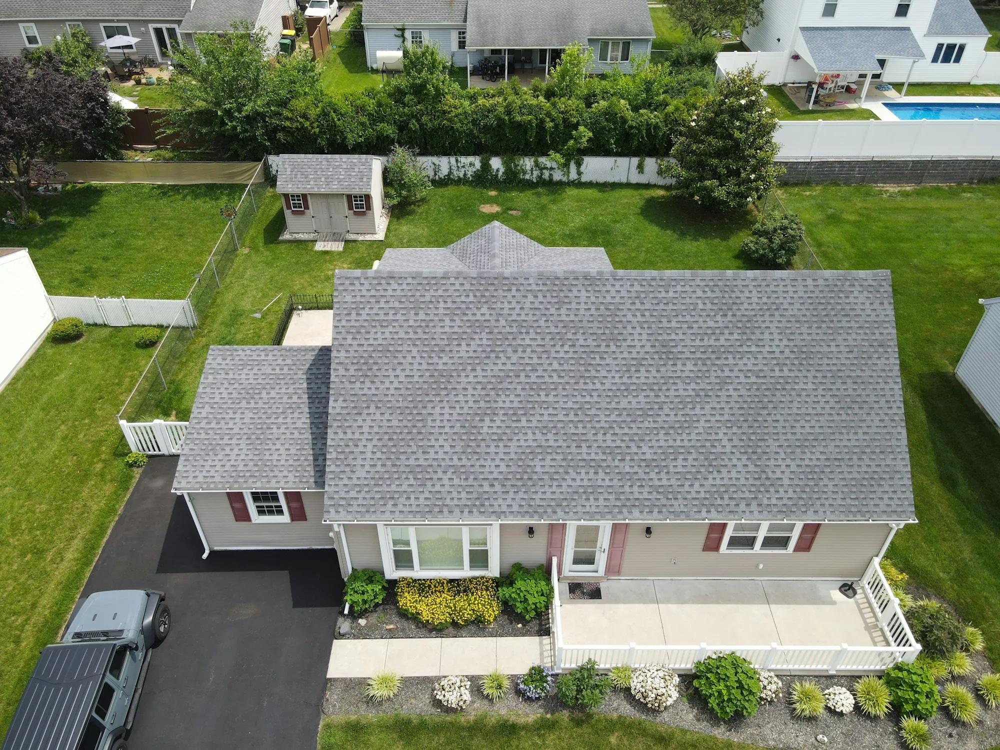 Aerial view of a gray shingle roof on a small house with a green lawn