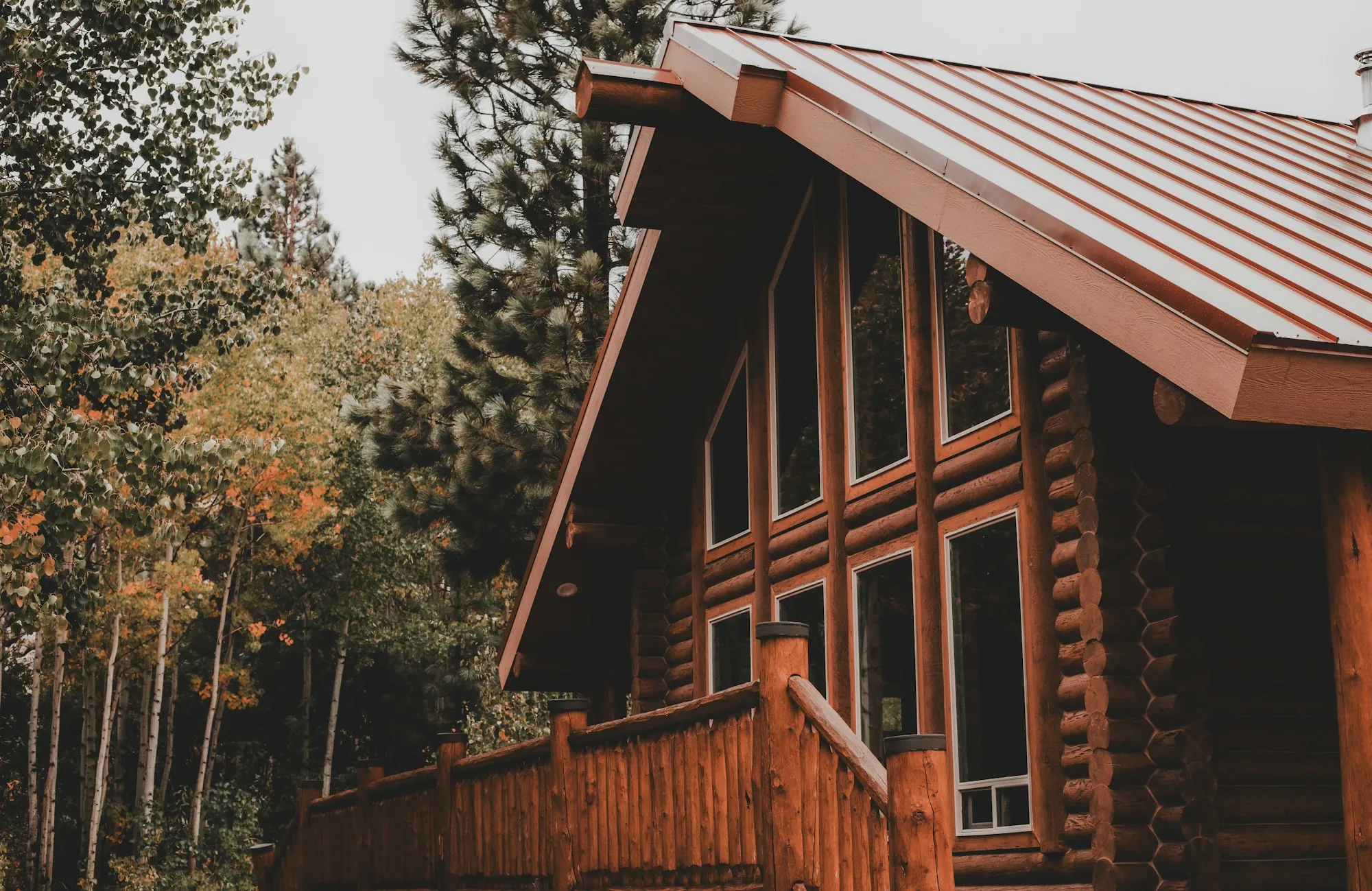 Log home with a metal roof in a wooded setting, illustrating the standing seam vs exposed fastener choice for Avondale Estates homes
